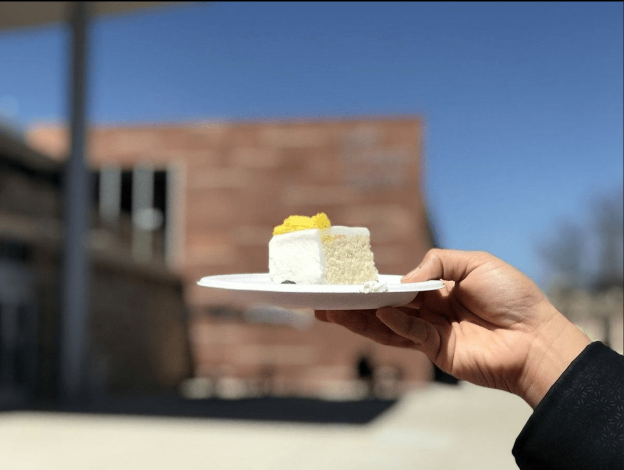A slice of cake being held up in front of the Lory Student Center